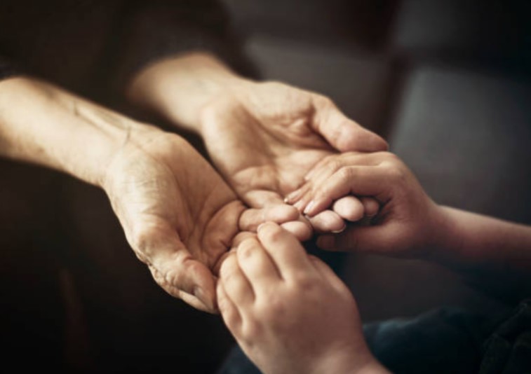 Elderly hands tenderly holding younger hands - connection across generations